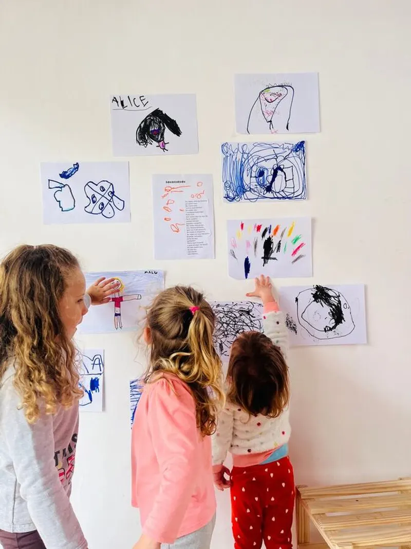 crianças pequenas observando desenhos na parede de um espaço brincante
